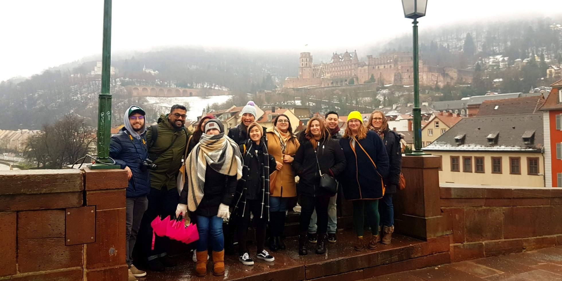 Eine Gruppe von internationalen Studierenden steht vor dem Heidelberger Schloss in einer winterlichen Atmosphäre