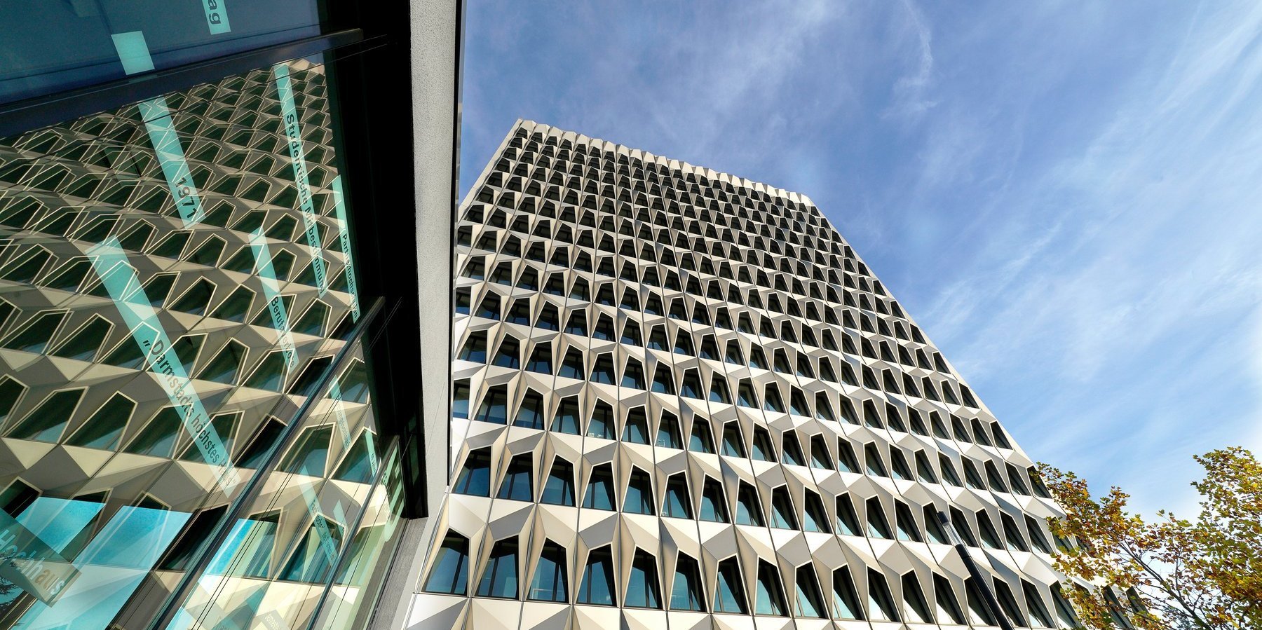 Das Hochhaus der h_da spiegelt sich im Fenster eines Gebäudes nebenan